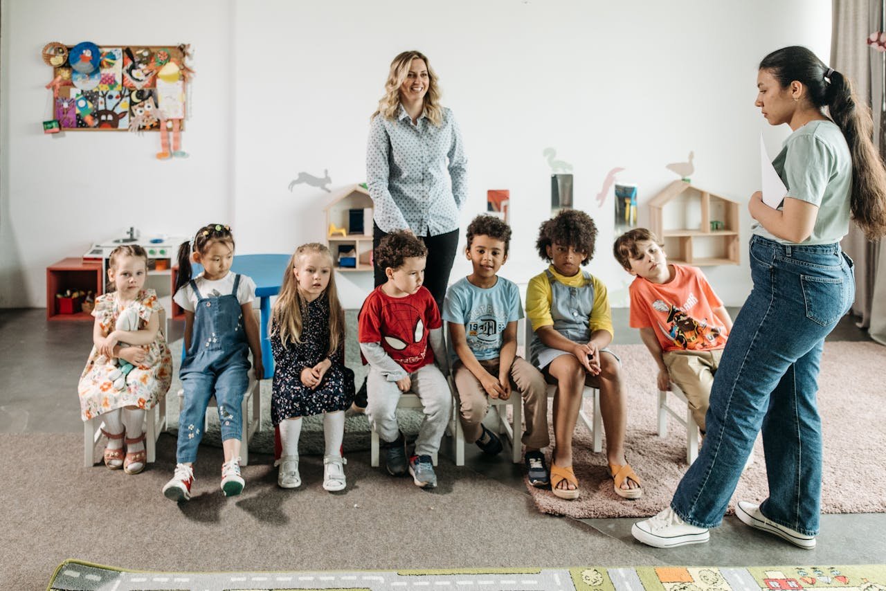 Group of children in a kindergarten classroom attending an interactive learning session with teachers.